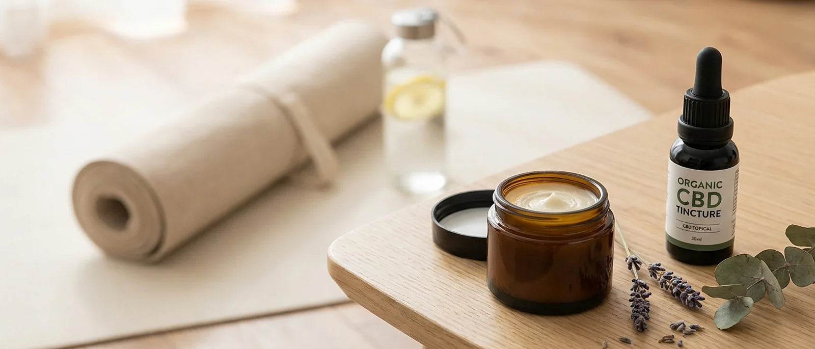 Natural CBD topical cream and CBD oil tincture bottle in post-workout recovery setting with wellness products