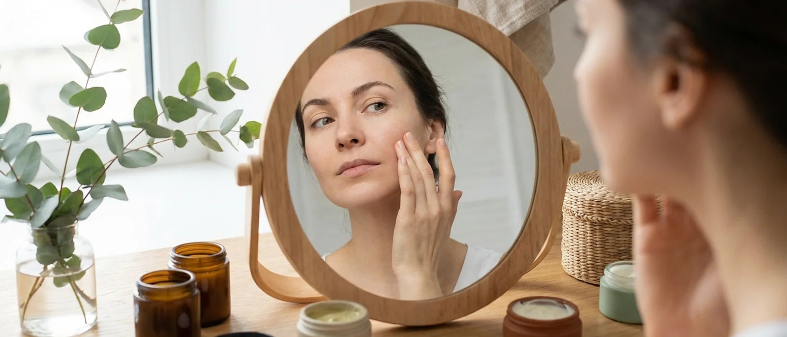 Woman examining her face in mirror while considering her skincare routine